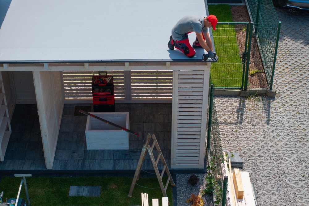 man in a red hat is installing a roof on a shed